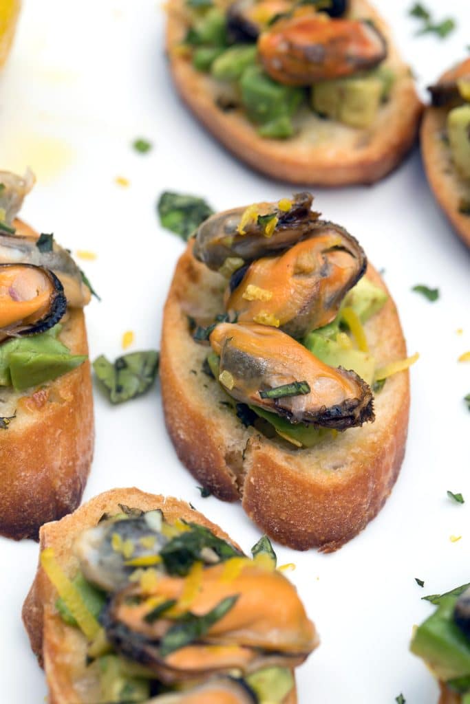 Sparkling Wine Mussel Crostini with Avocado, Grilled Lemon, and Basil -- The perfect party appetizer #GloriousBites | wearenotmartha.com