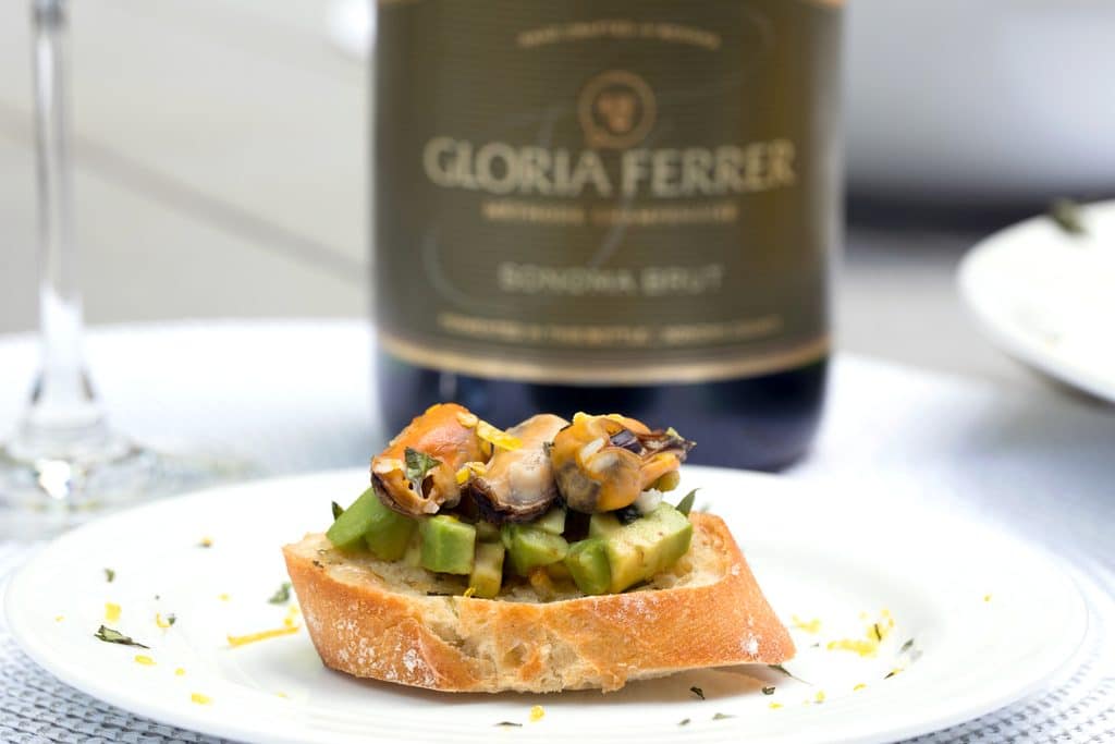 Sparkling Wine Mussel Crostini with Avocado, Grilled Lemon, and Basil -- The perfect party appetizer #GloriousBites | wearenotmartha.com