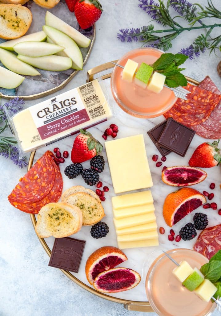 Overhead view of cheese board with lots of fruit, meat, chocolate, and crackers and pear old cubans for cheese and cocktail pairing party