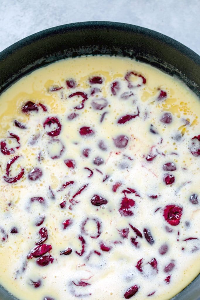 Overhead view of cherry clafoutis batter in skillet before baking