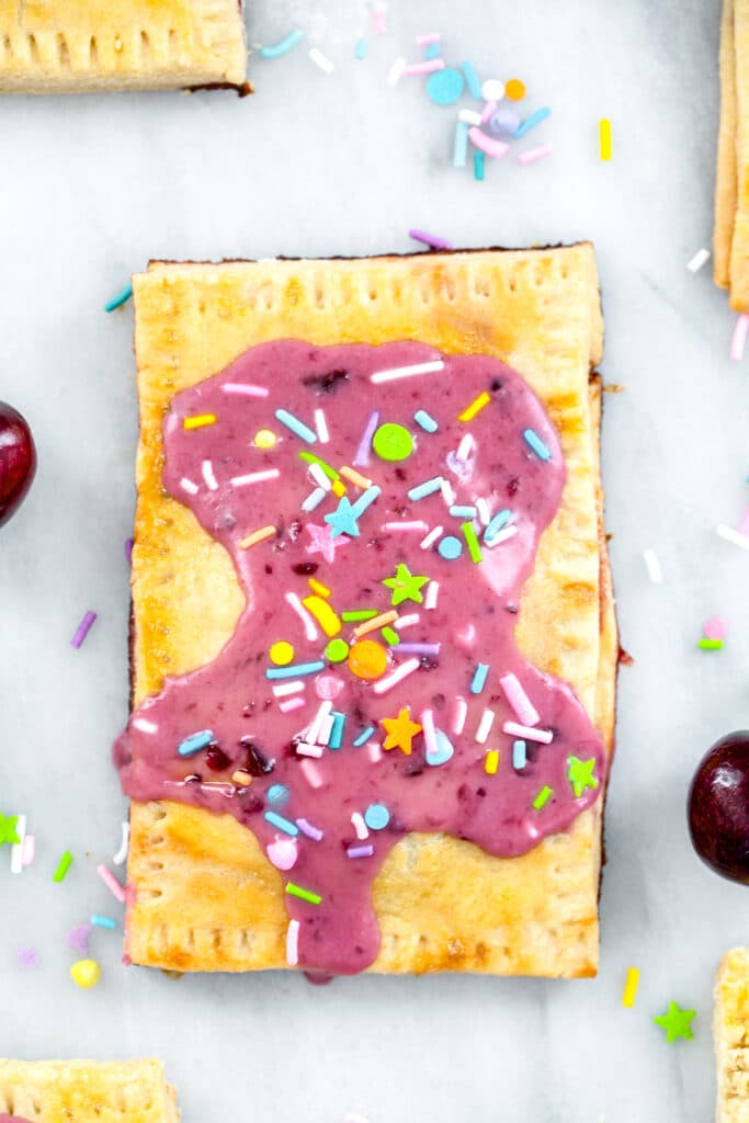 Close-up overhead view of a cherry lime pop tart with cherry icing and sprinkles on a marble surface