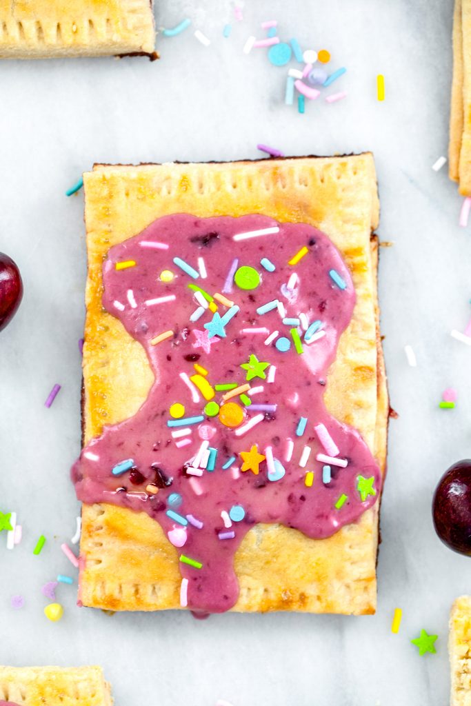 Close-up overhead view of a cherry lime pop tart with cherry icing and sprinkles on a marble surface