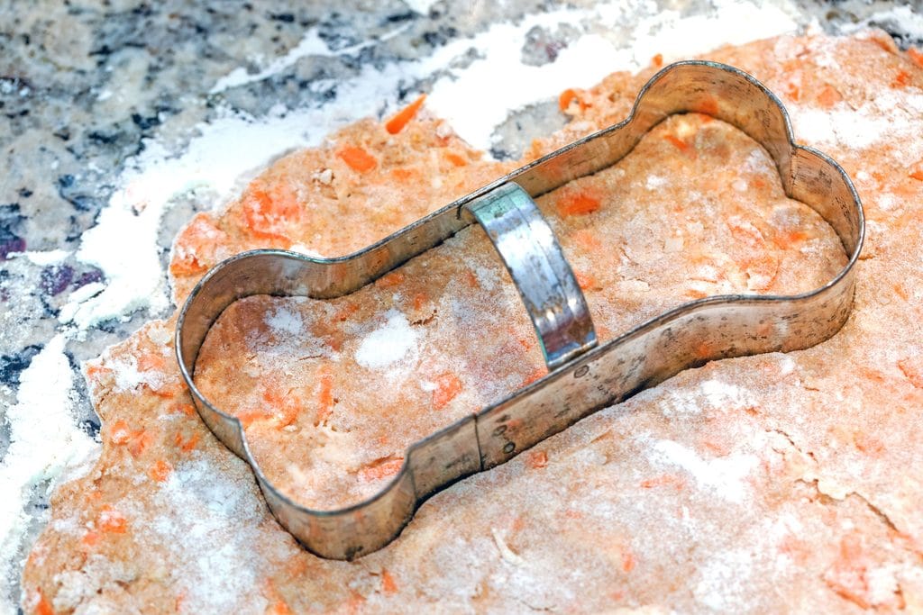 Treat dough rolled out on a floured surface with a dog bone cookie cutter