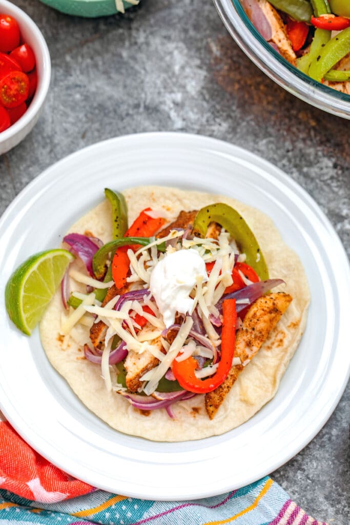 Overhead closeup view of a prepared chicken fajita on a plate topped with sour cream