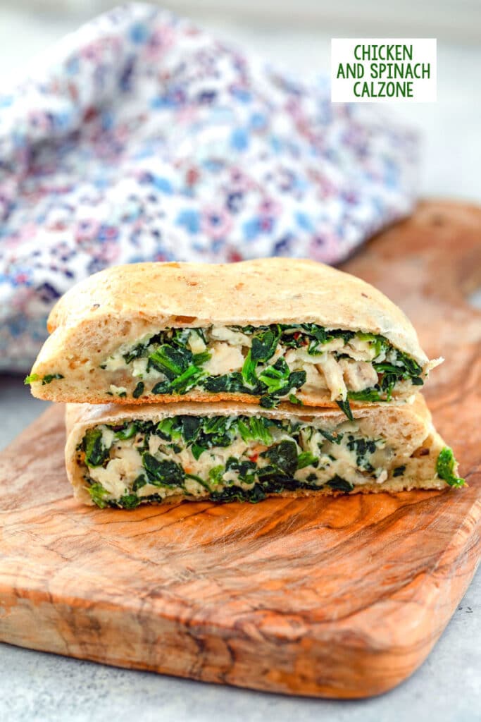 Head-on view of a chicken and spinach calzone cut in half and stacked on a wood cutting board with recipe title at top