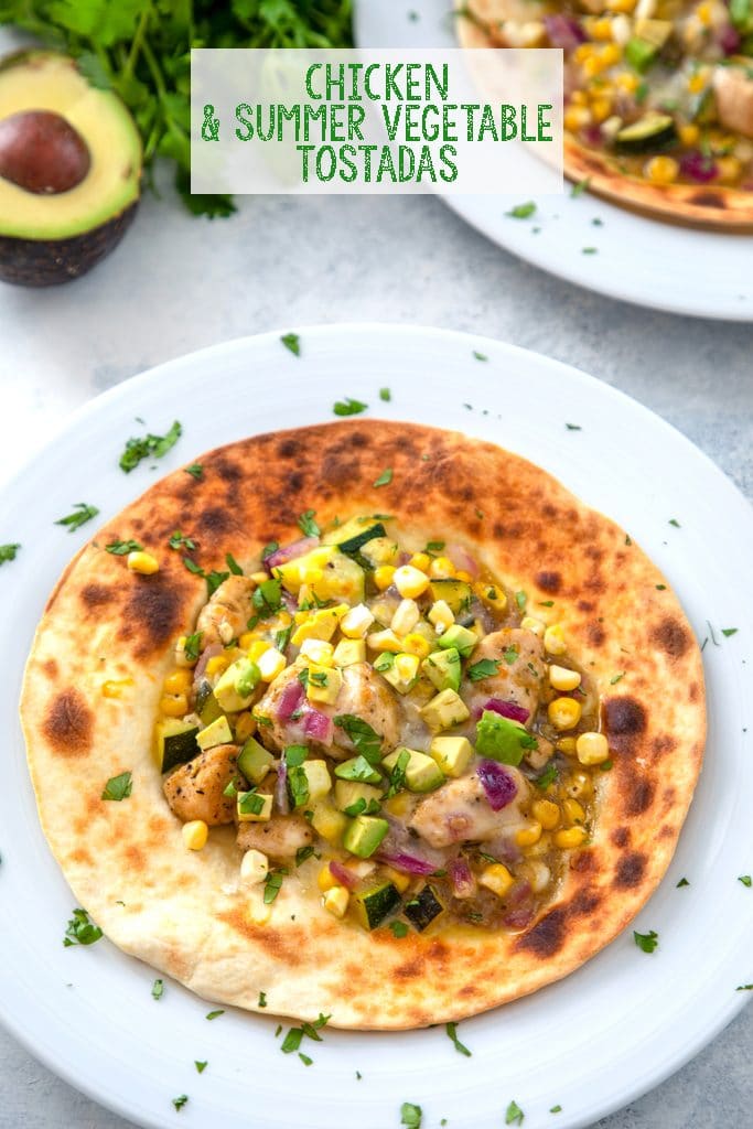 Overhead view of chicken and summer vegetable tostadas topped with avocado and cheese with avocado and cilantro in the background and "Chicken and Summer Vegetable Tostadas" text at top