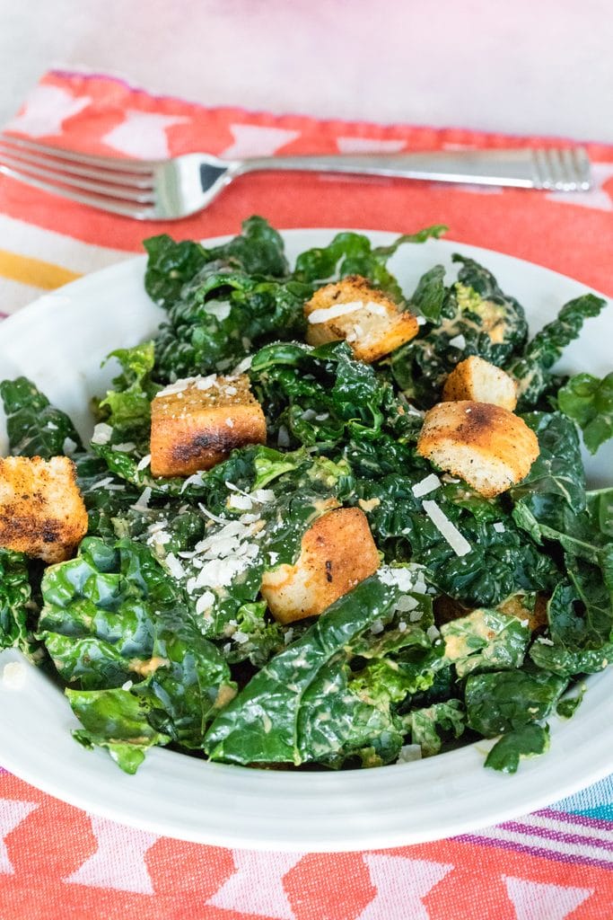 Closeup of chipotle kale Caesar salad on red towel with fork in the background