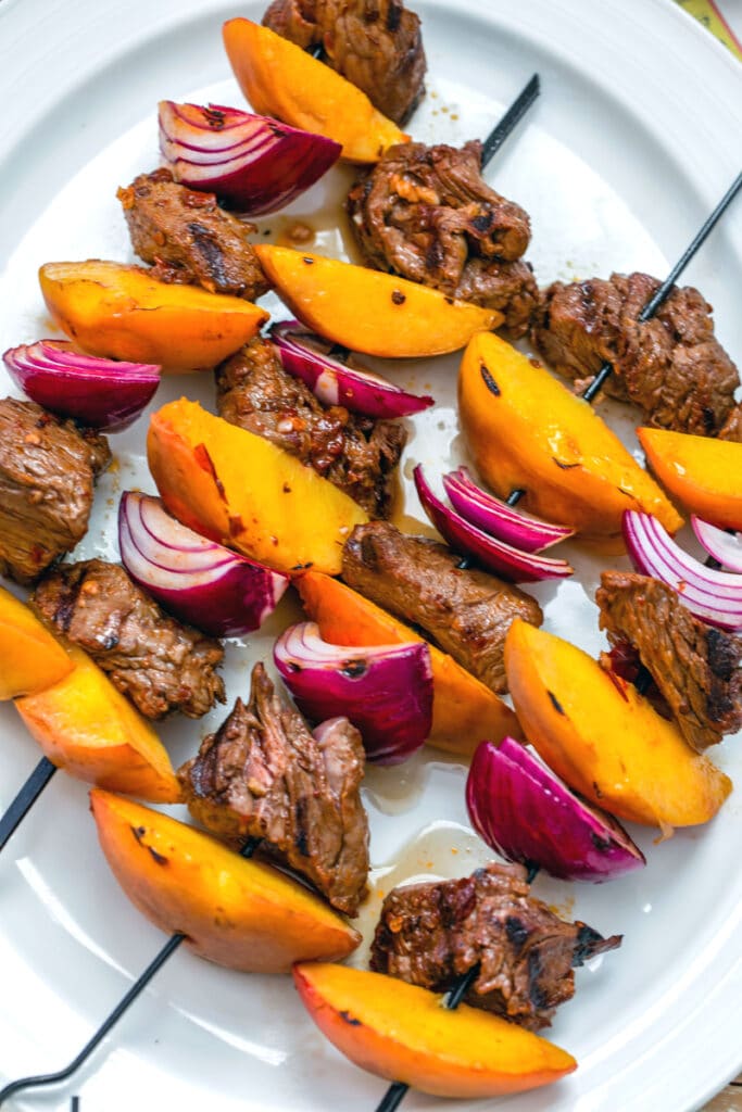 Overhead closeup of Chipotle Stteak and Peach Kabobs on platter just off the grill