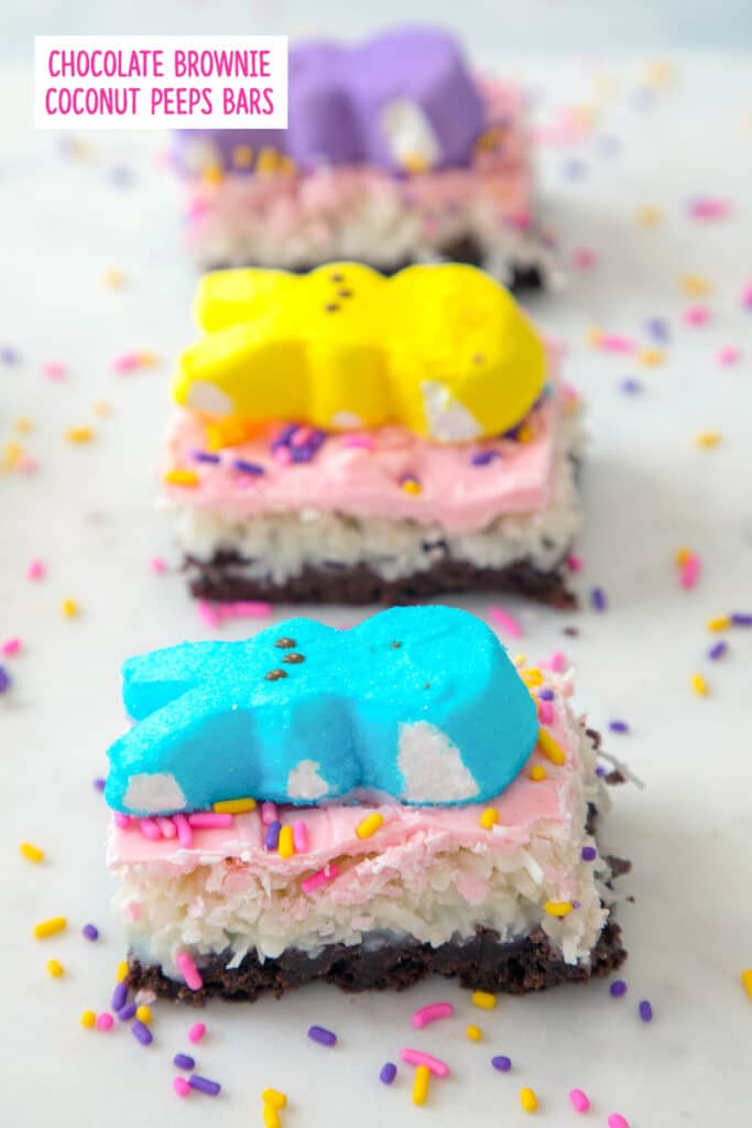 Head-on view of a row of Peeps brownie bars with coconut, pink icing, and Peeps on top with sprinkles all around with recipe title at top