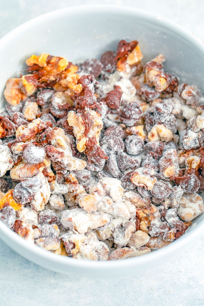 Chocolate chips and walnuts in a bowl tossed with flour.