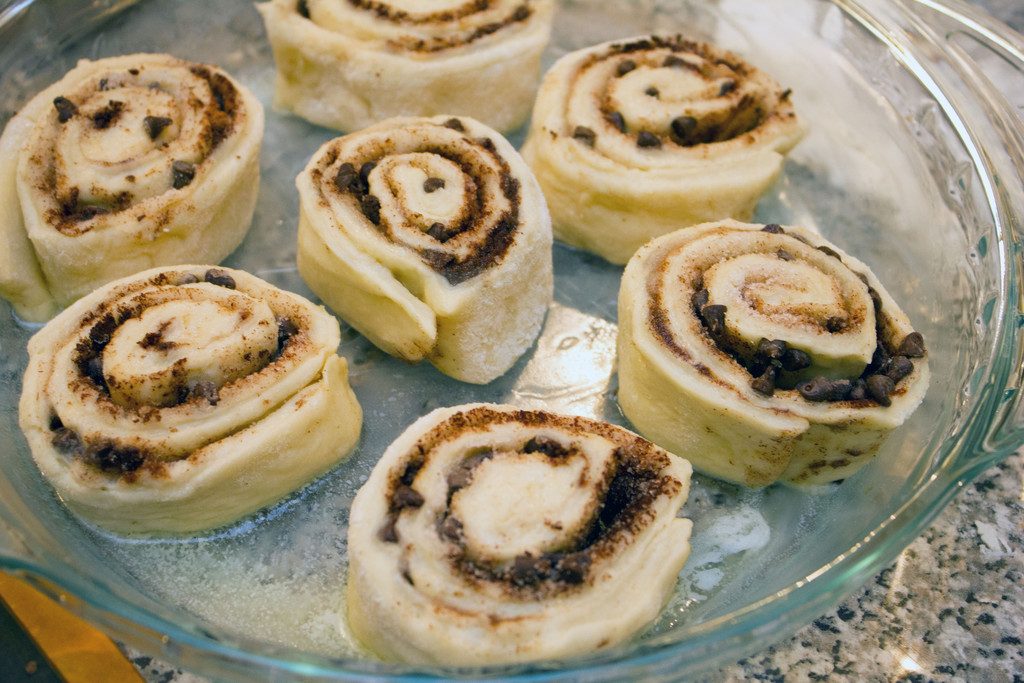 View of cinnamon rolls sitting in buttered pie plate before being baked