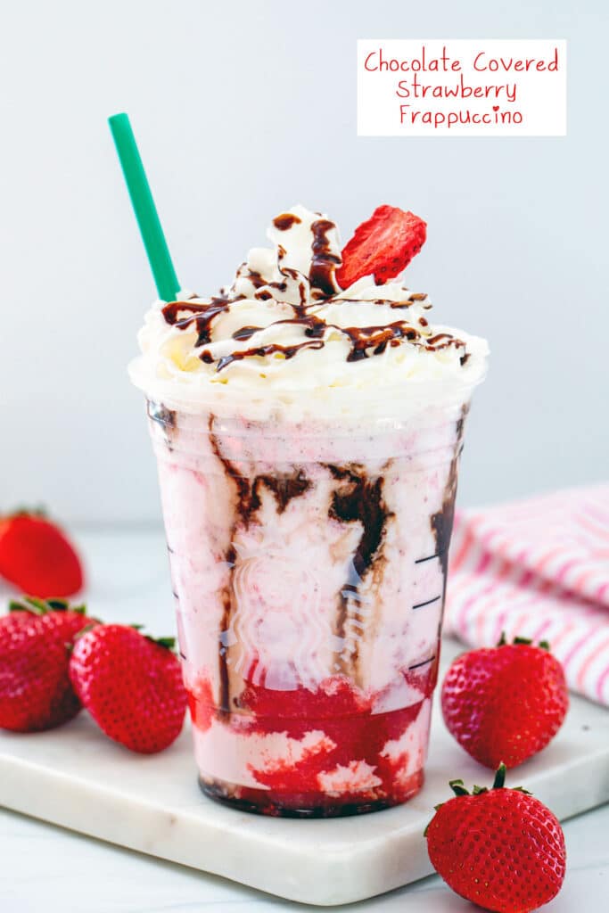 Head-on view of a chocolate covered strawberry frappuccino with strawberry and mocha syrup and a whipped cream topping with strawberries all around and recipe title at top