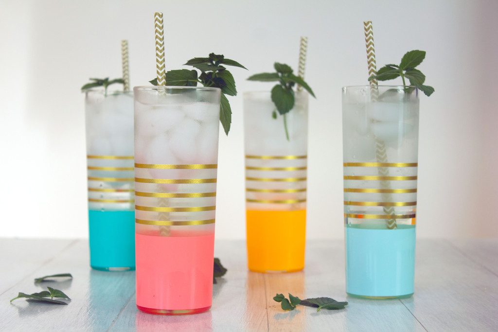 Landscape view of four colorful glasses of chocolate mint coconut gin syrup with gold and white straws with chocolate mint garnishes