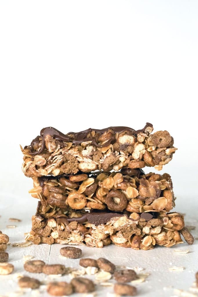 Stack of three peanut butter cheerios granola bars with cereal and oats all around