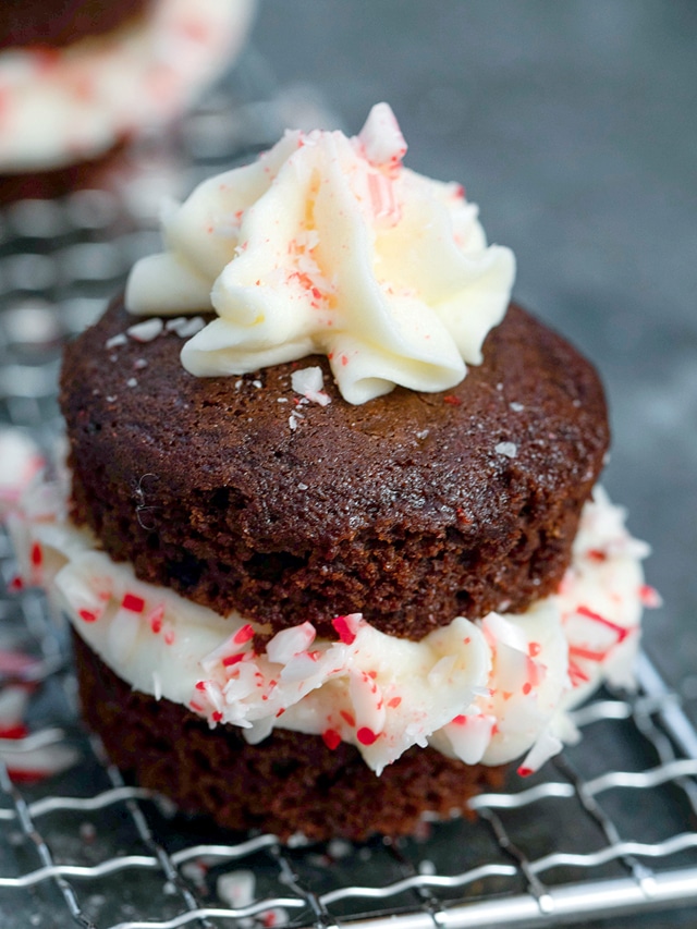 Head-on closeup view of a chocolate peppermint cupcake with frosting and crushed candy canes on top and in middle of cupcake