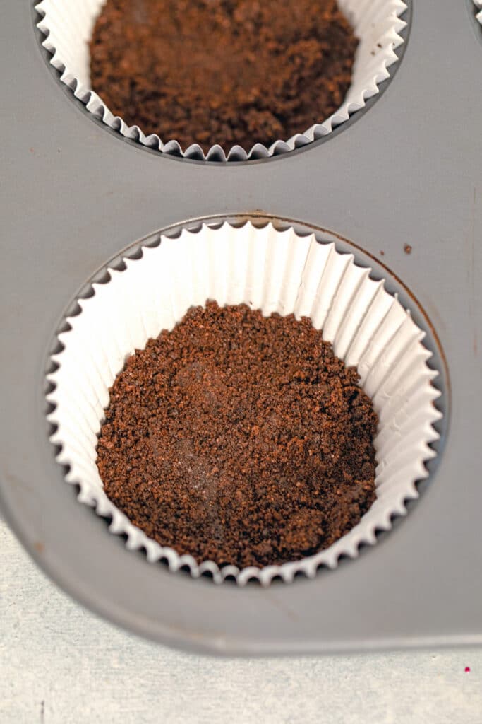 Oreo cookie crumbs pressed into cupcake papers in tin