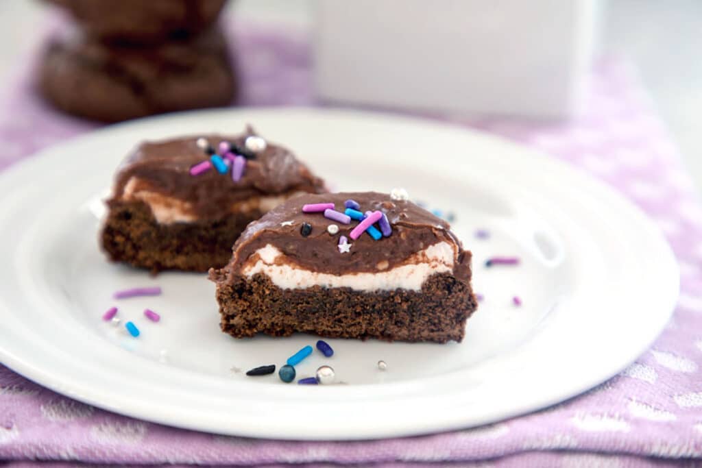 Head-on landscape view of two chocolate surprise cookies cup open to show marshmallow center