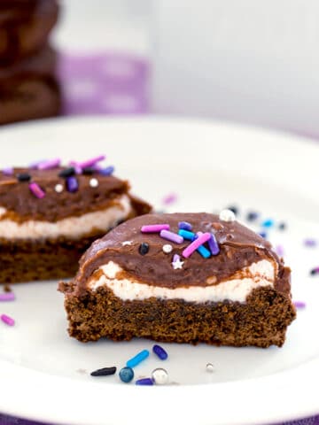 A chocolate surprise cookie cut in half showing marshmallow filling with sprinkles all around