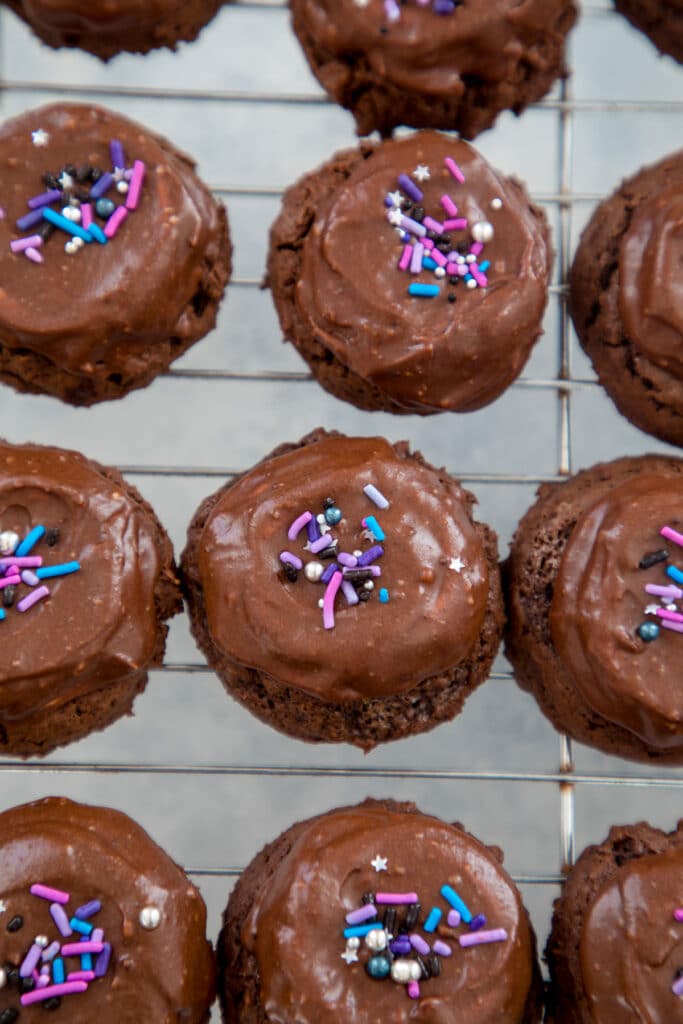 Baking rack filled with chocolate surprise cookies topped with pink and purple sprinkles