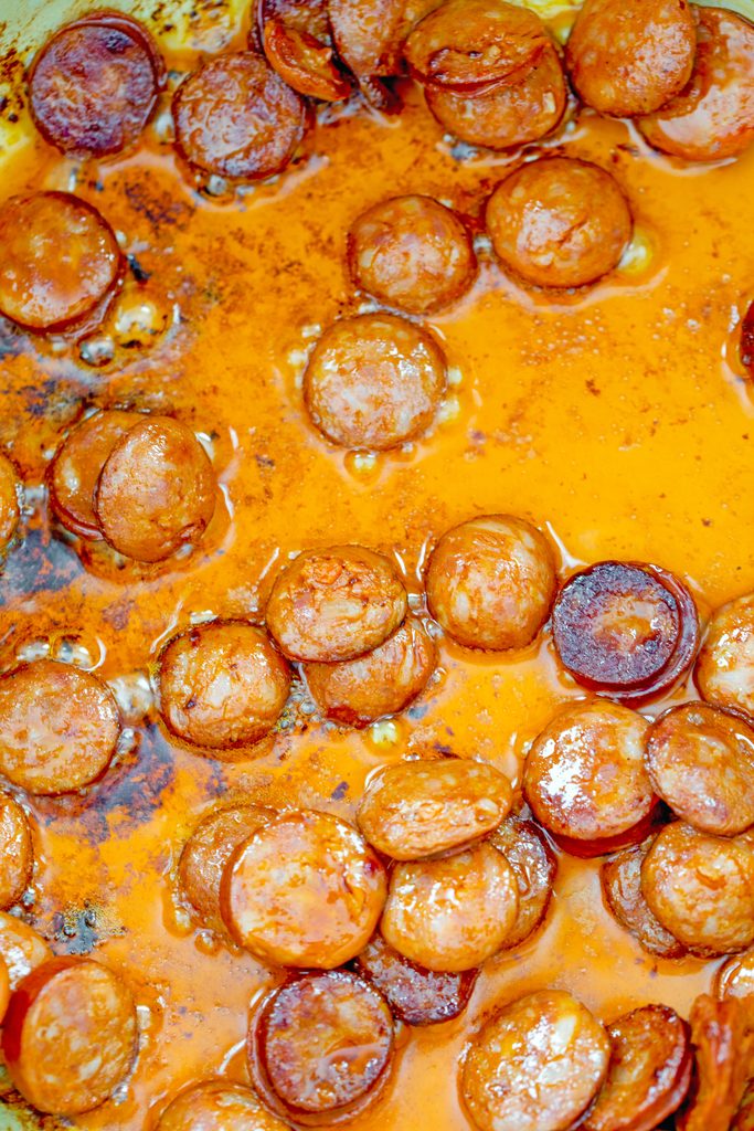 Overhead view of sliced chorizo cooking in its oils in a pot
