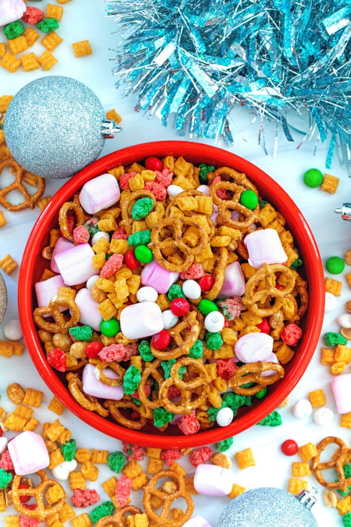 Overhead view of a bowl of Christmas trail mix with trail mix and ornaments on the table