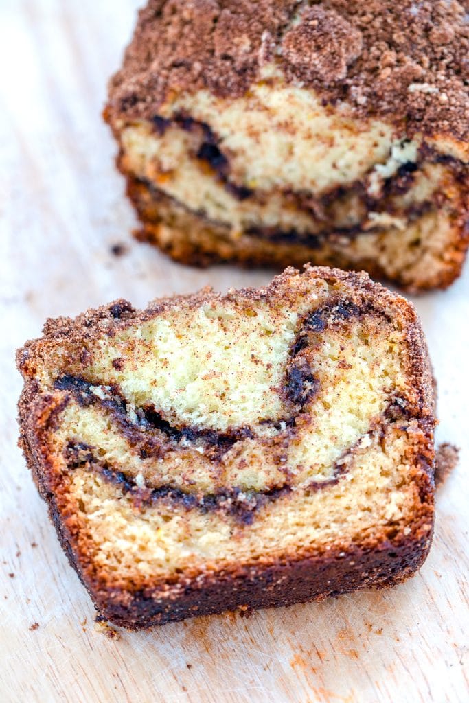 Overhead closeup view of a slice of cinnamon loaf cake with cinnamon swirl with the rest of the loaf in the background
