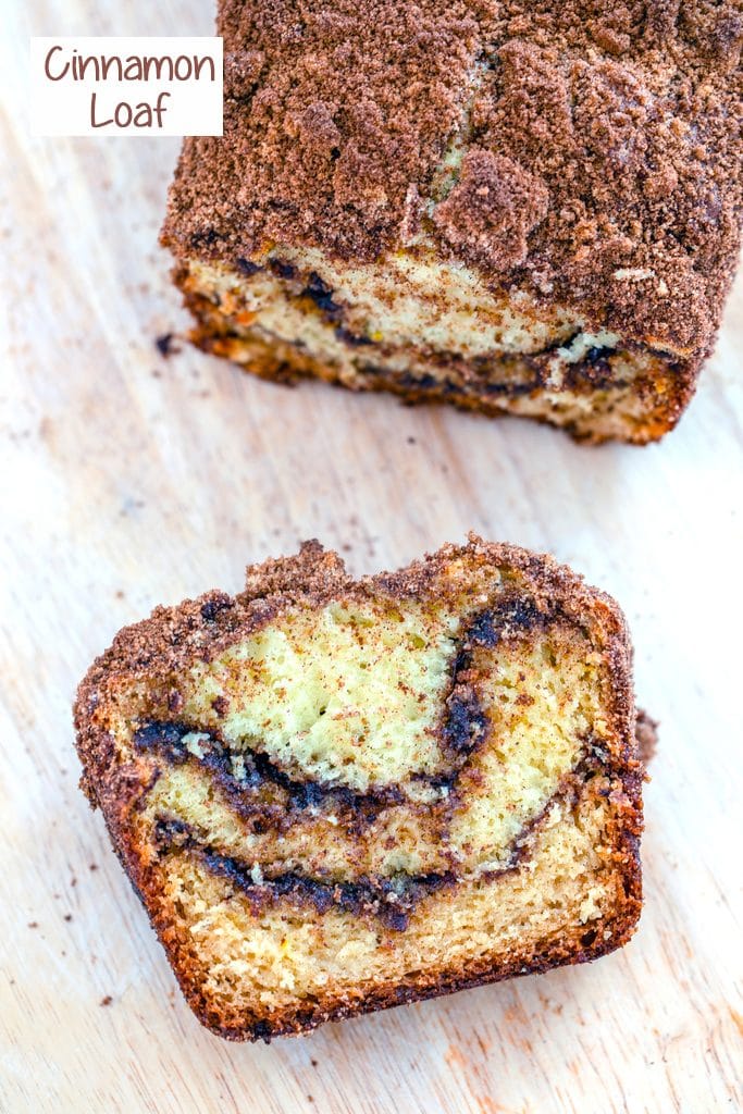 Overhead view of a slice of cinnamon loaf cake on a wooden cutting board with the rest of the loaf in the background and recipe title at top