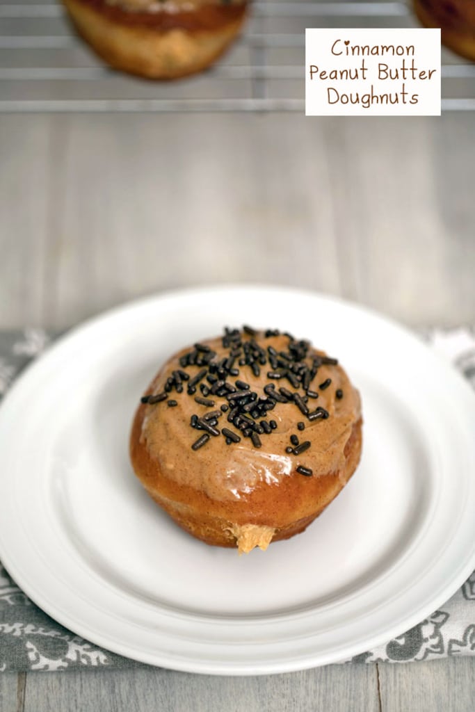 Overhead view of a cinnamon doughnut on a white plate and topped with peanut butter glaze and chocolate sprinkles with peanut butter cream filling peeping out with recipe title at top.