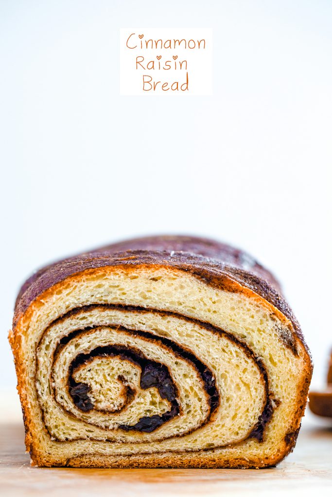 Head-on view of a loaf of cinnamon raisin bread showing the perfect cinnamon swirl with recipe title at top of image
