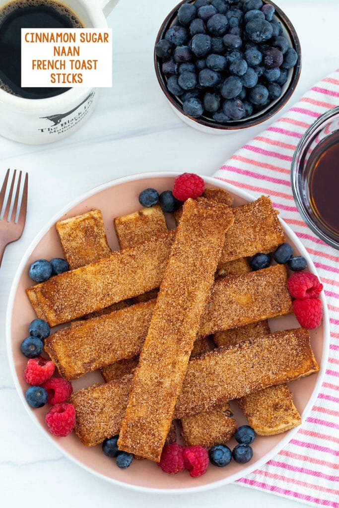 Overhead view of cinnamon sugar naan french toast sticks with bowl of blueberries and cup of coffee in background and recipe title at top.