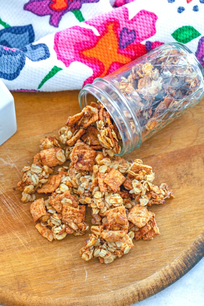Cinnamon Toast Crunch granola spilling out of a jar on a wooden board