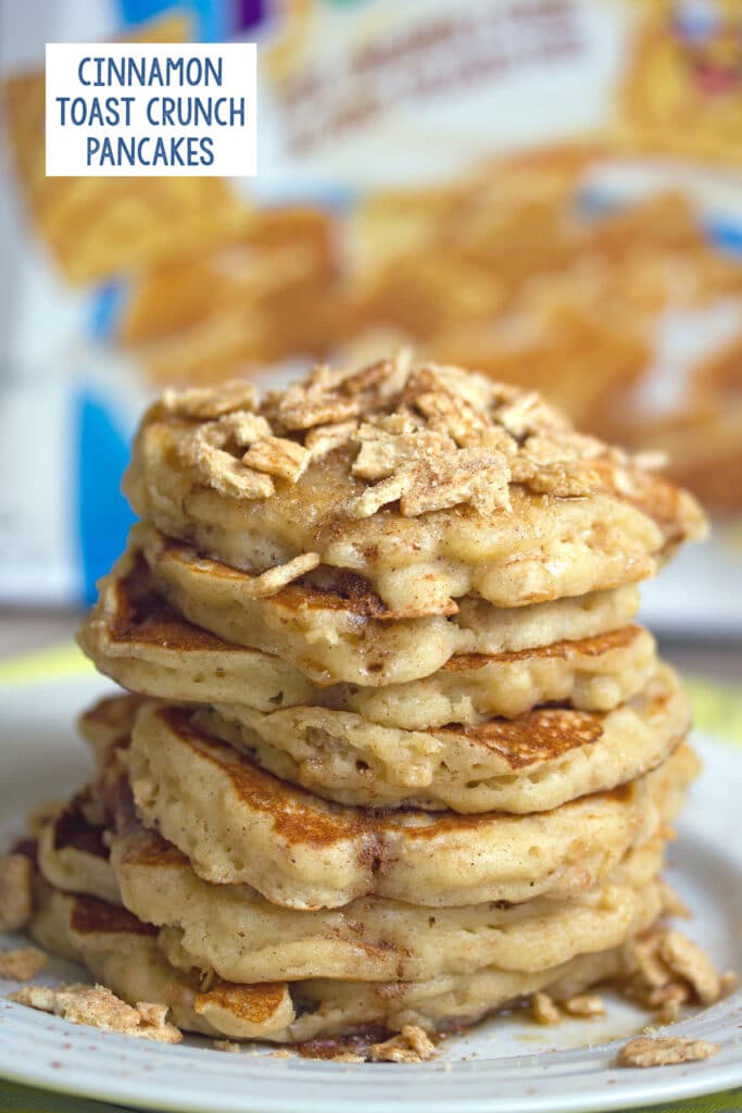 Head-on view of a stack of Cinnamon Toast Crunch pancakes topped with the cereal with the box in the background and recipe title at top