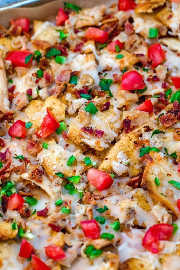 overhead close-up view of clam nachos with jalapeño, tomato, and bacon