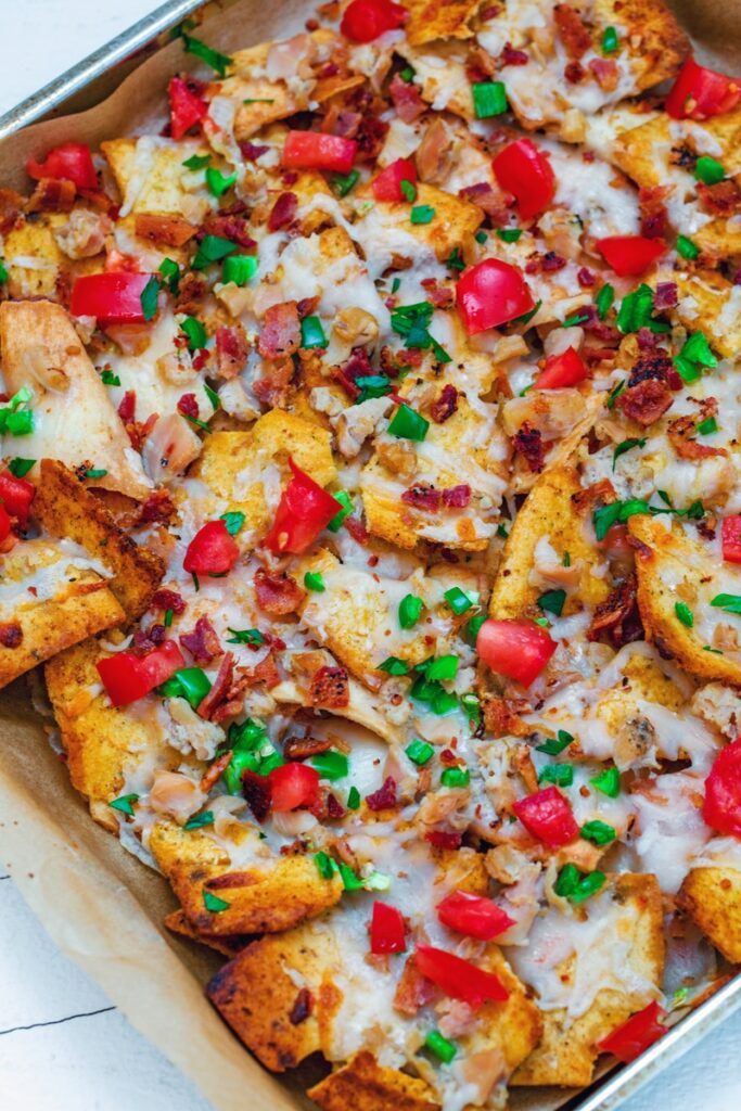 Clam nachos just out of the oven with chopped clams, melted cheese, bacon, jalapeño, and tomatoes