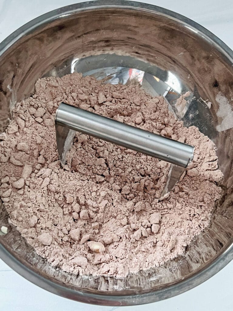 Cocoa powder, flour, and chopped butter in mixing bowl with pastry blender.