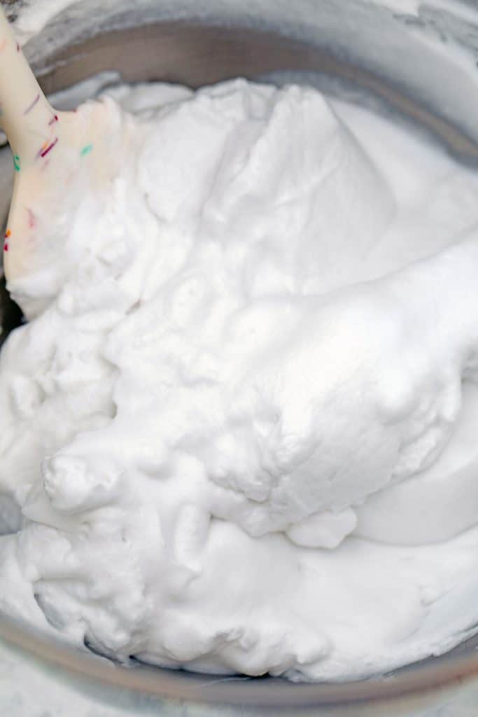 Overhead view of coconut cream whipped cream in a mixing bowl with spatula