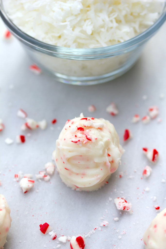 Coconut Candy Cane Truffle surrounded by crushed candy canes with a bowl of shredded coconut in the background
