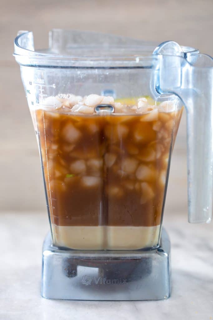 Vitamix blender filled with coffee, ice, avocado, condensed milk, and vanilla