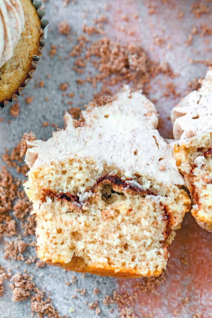 Overhead view of a coffee cake cupcake cut in half with cinnamon swirl and buttercream frosting visible