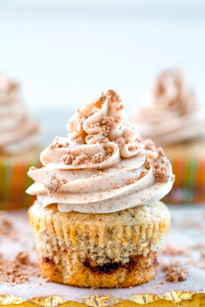 Head-on close-up view of a coffee cake cupcake with cinnamon swirl, cinnamon frosting and crumb topping.