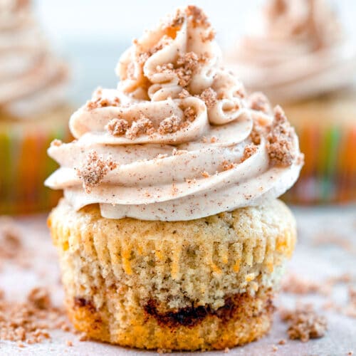 Head-on close-up view of a coffee cake cupcake with cinnamon swirl, cinnamon frosting and crumb topping.