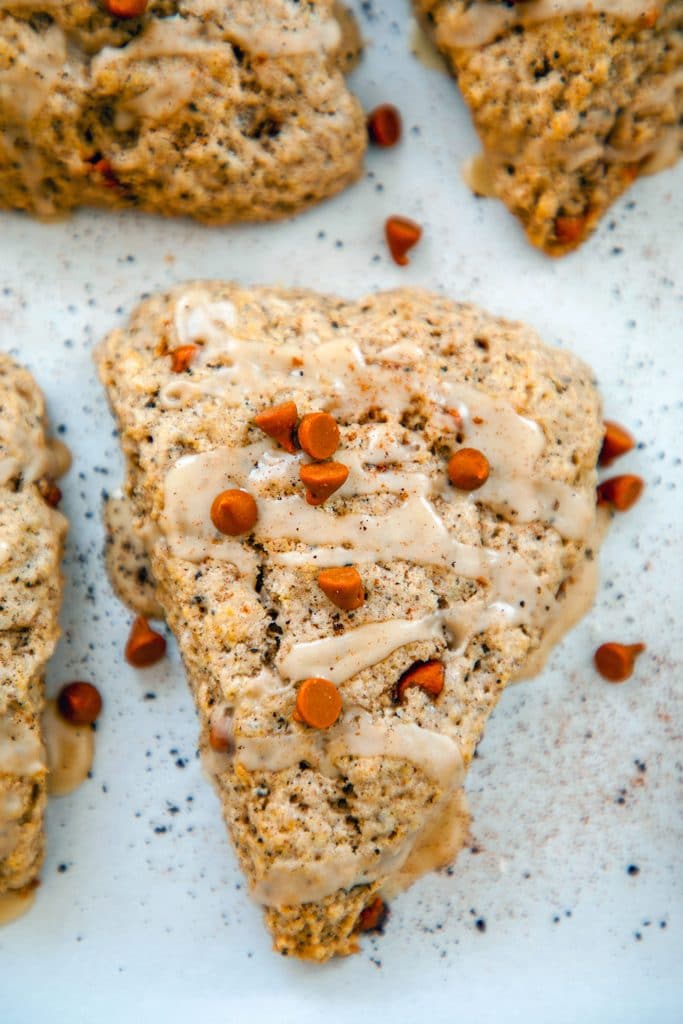 Closeup bird's eye view of coffee cinnamon scones topped with cinnamon chips on a parchment-lined baking sheet