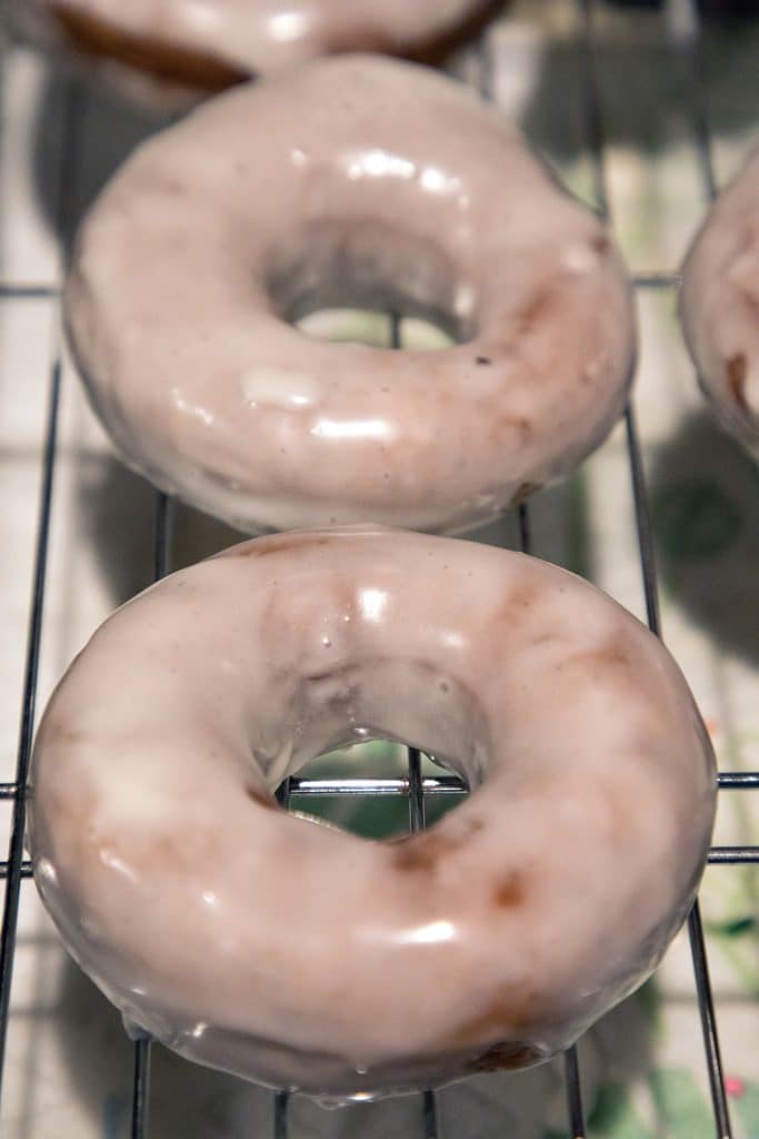 Coffee flavored donuts with glaze resting on cooling rack