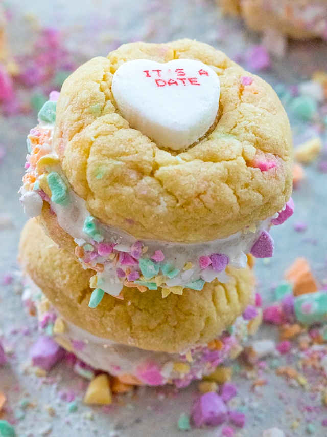 Overhead view of conversation heart cookies stacked on each other with crushed candies all around.