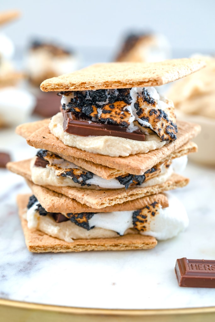 Head-on close-up view of three cookie dough s'mores stacked on top of each other on marble tray