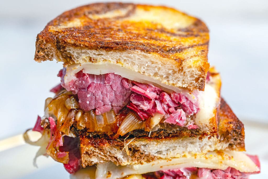 Landscape view of a close-up of a sliced half of a corned beef melt sandwich