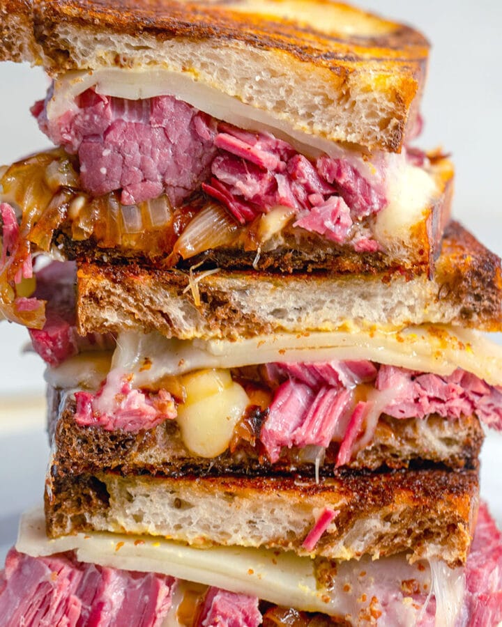 Close-up view of corned beef melt sandwich halves stacked one each other
