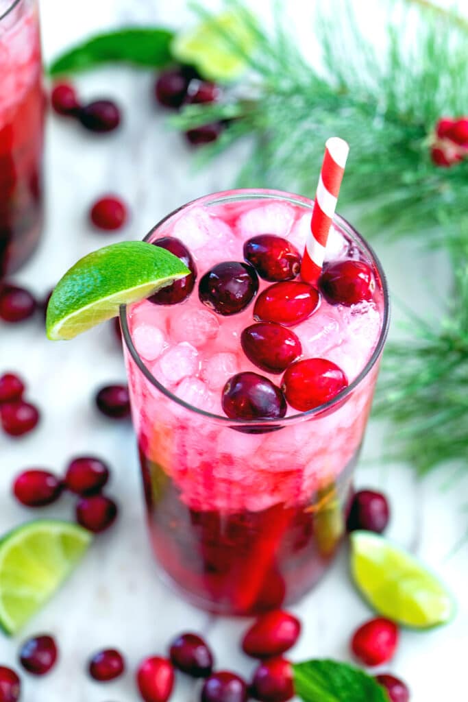 Closeup view of cranberry mojito with holly, cranberries, and sliced limes