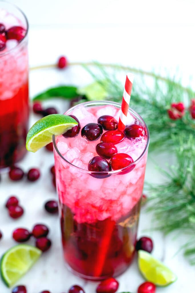 View of cranberry mojito with holly, cranberries, and sliced limes