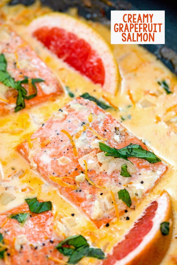 Overhead closeup view of creamy grapefruit salmon in a skillet with basil, grapefruit wedges, and a grapefruit cream sauce with recipe title at top.